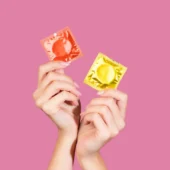 A imagem mostra só as mãos de uma pessoa segurando duas das melhores camisinhas.