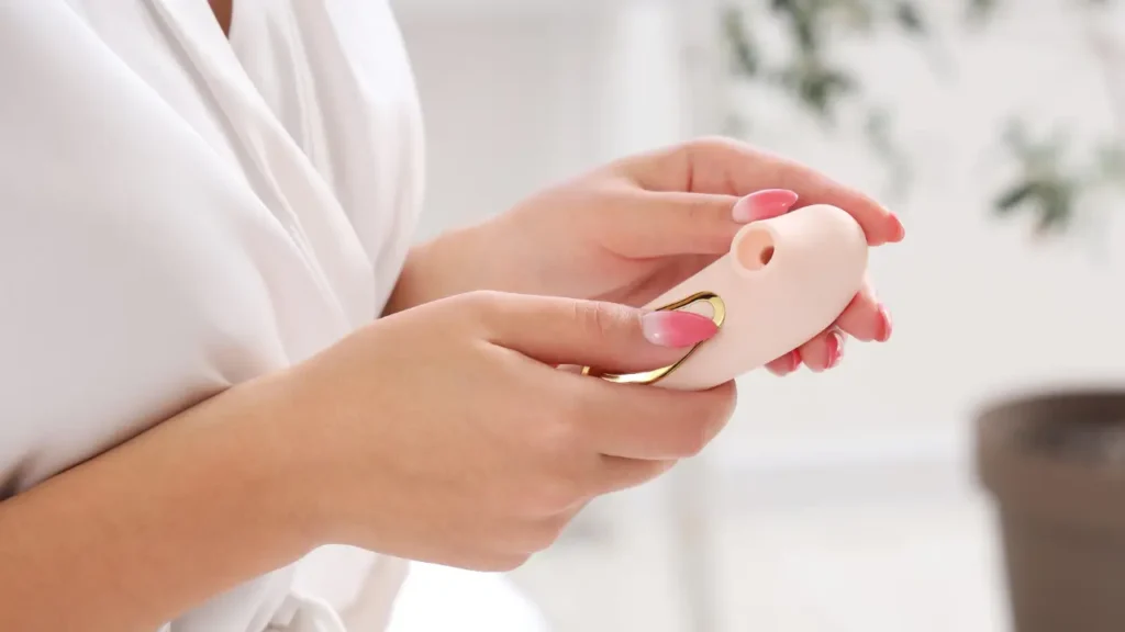 13 melhores vibradores femininos (e mais vendidos) de 2026 A imagem mostra as mãos de uma mulher segurando um vibrador sugador.