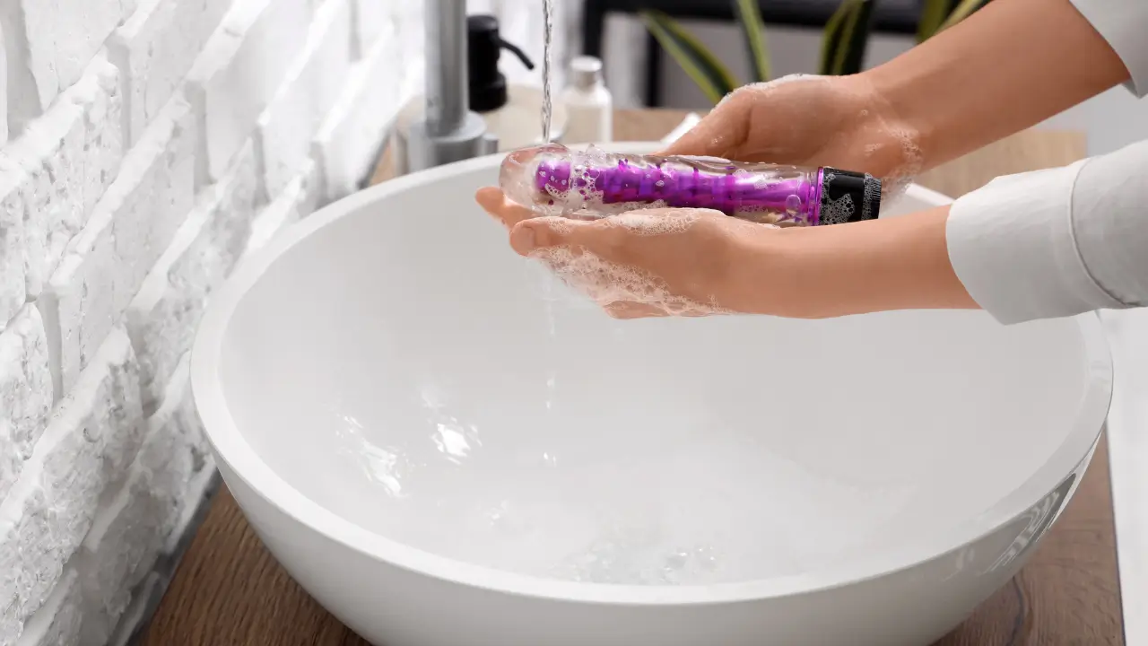 Como higienizar um vibrador da forma certa? 7 passos simples Pessoa higienizando uma vibrador com sabão.